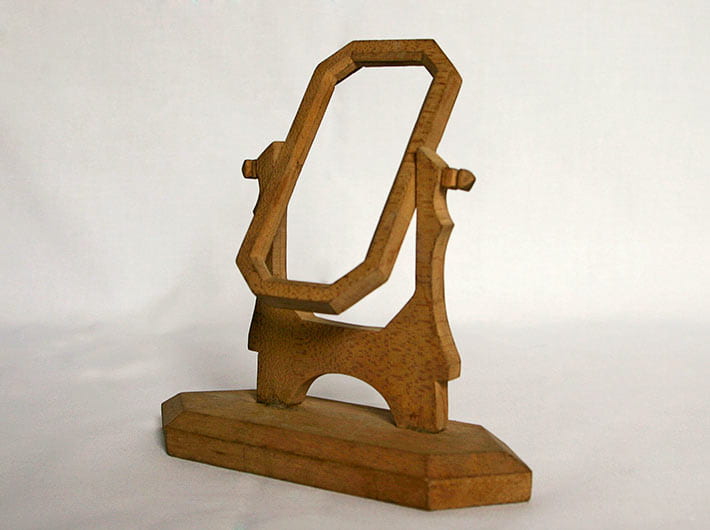 Wooden mirror/picture frame, unstained, made in Camp Petawawa,1940-1942. The frame is constructed entirely of wood, with 3 main parts: the pivoting frame, the frame support, and the base. The frame itself is an elongated octagon (4.6 inches high, 2.5 inches wide). The long base is bevelled. Both ends are pointed, resulting in a shape that resembles a rectangle with two triangles on the end. The base measures 7 inches long, 2 inches wide, and .8 inches high. A metal insert, which was reflective and likely used as a mirror, was cut to the measurements of the frame and repurposed from a cigarette tin. This frame is part of a group of four collected and preserved by the family of internee Girolamo (George) Capponi. The frames along with other wooden objects in the collection, may have been made by Capponi himself. He had written to his wife asking for wood-working tools.