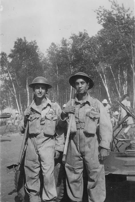 Photograph of Rino & Philip Albanese, at military training in Petawawa, ON, ca. 1943. At the age of 18, Rino Albanese and his twin Philip enlisted in active service with the Canadian military. They were trained at Petawawa, where most of the about 600 Italian Canadian internees were housed. At the same time, the twin's father, Giovanni was designated as an enemy alien. The brothers were sent overseas where they served with the Canadian forces in England, Holland, and Germany.